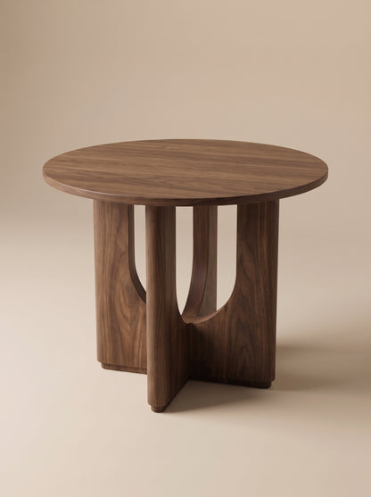 Supellex Home mesa auxiliar redonda Bosco en madera maciza de nogal con tapa circular y base en cruz con aperturas curvas caladas - vista en perspectiva
