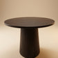 Supellex Home mesa auxiliar redonda Ero fabricada en madera nogal oscuro con tapa circular lisa y pedestal cónico acanalado - vista frontal en perspectiva