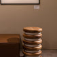 Supellex Home mesa auxiliar cilíndrica Querqus en madera natural de nogal y anillos blancos ubicada en espacio de exhibición junto a mobiliario contemporáneo