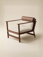 Supellex Home poltrona Oshi tapizada en tela color beige con rodillo de apoyo en cuero marrón y estructura en madera nogal - vista en perspectiva tres cuartos