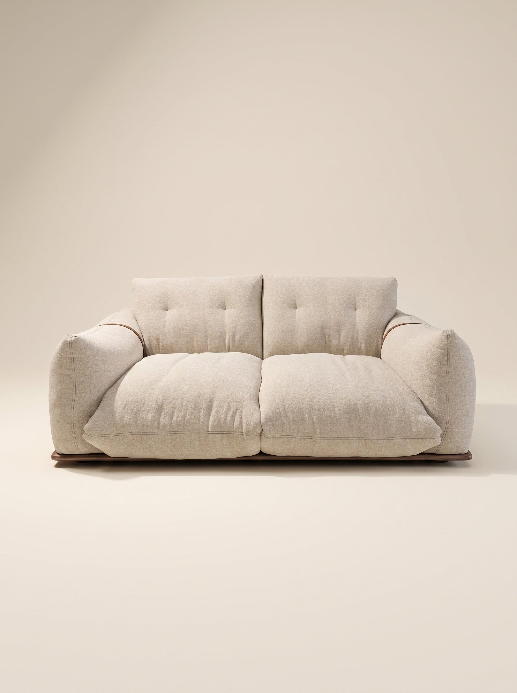Sofá de dos plazas Cluddo de silueta mullida y perfil bajo tapizado en tela texturizada beige claro con base de madera a ras de suelo.