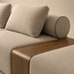 Sofá modular de tres plazas Galo tapizado en tela beige con ribetes oscuros, respaldo cilíndrico con correas de cuero y cojines decorativos.