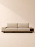 Sofá lineal Magen tapizado en lino beige claro con mesa auxiliar lateral de madera integrada tipo nicho y base de madera natural.